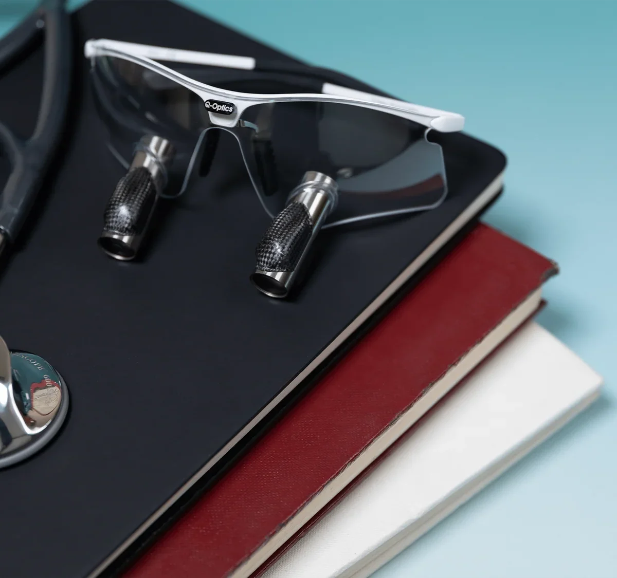 Q-Optics loupes on stack of books